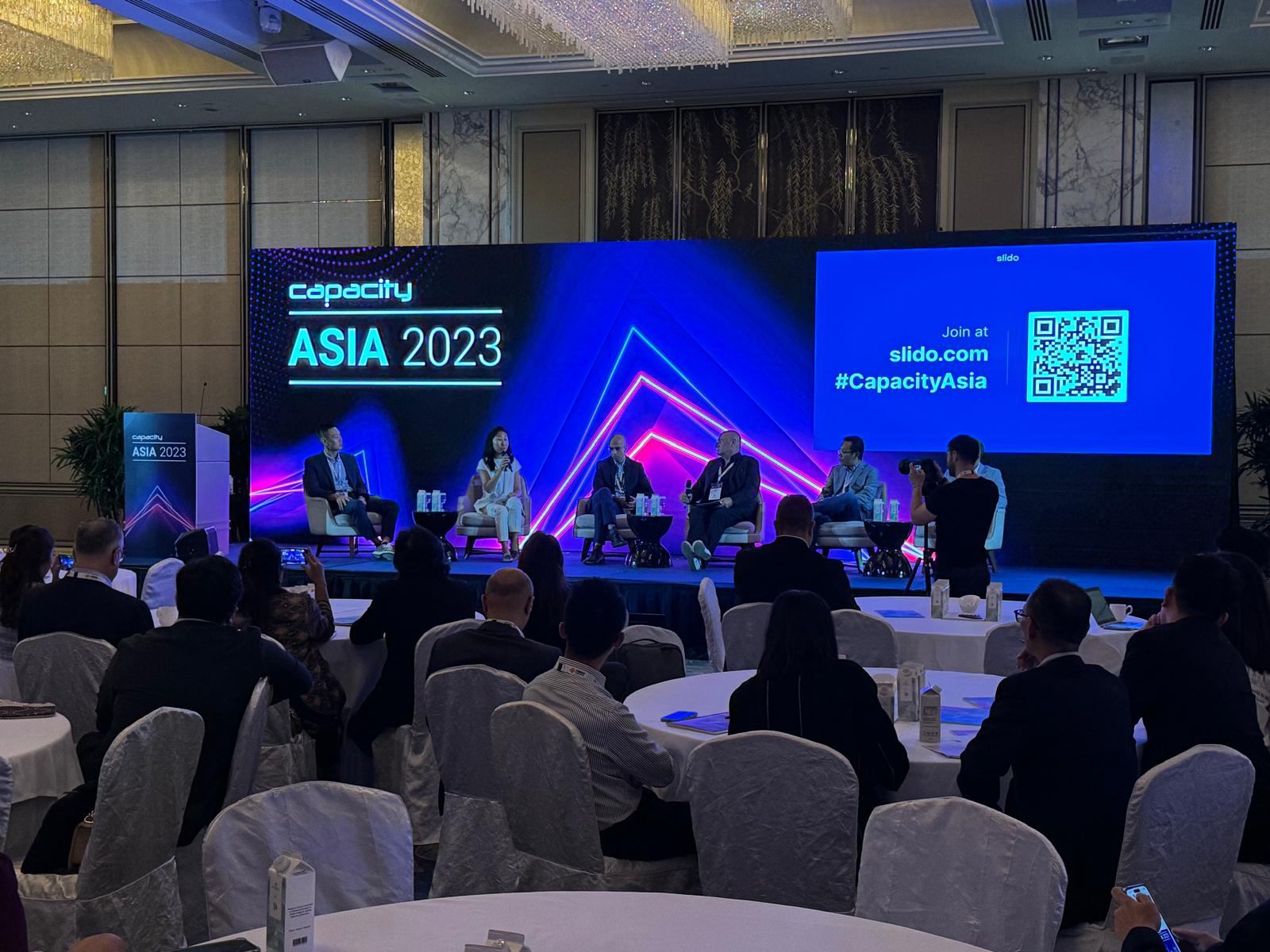 Conference fireside panel with a live audience polling QR code shown beside the stage