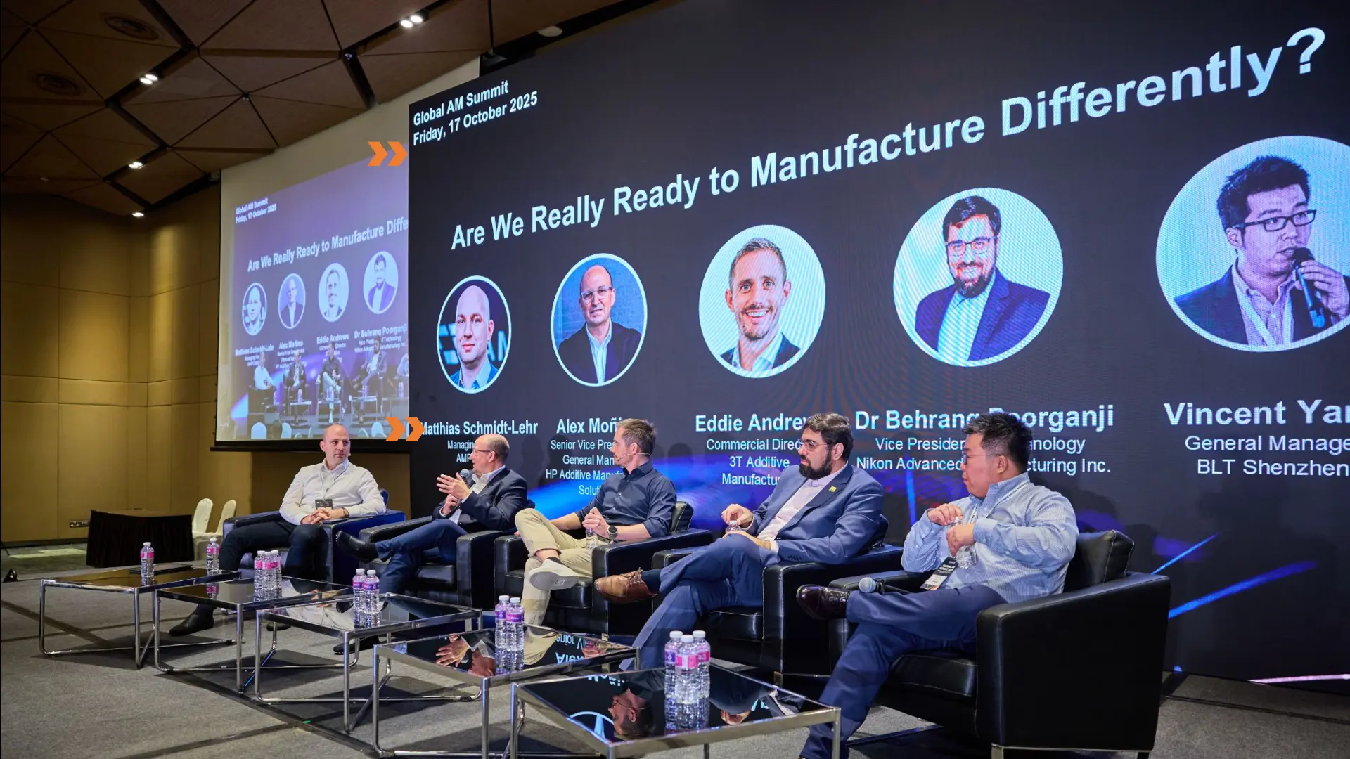 Panel discussion on stage with a wide LED wall showing speaker profiles at a Singapore summit