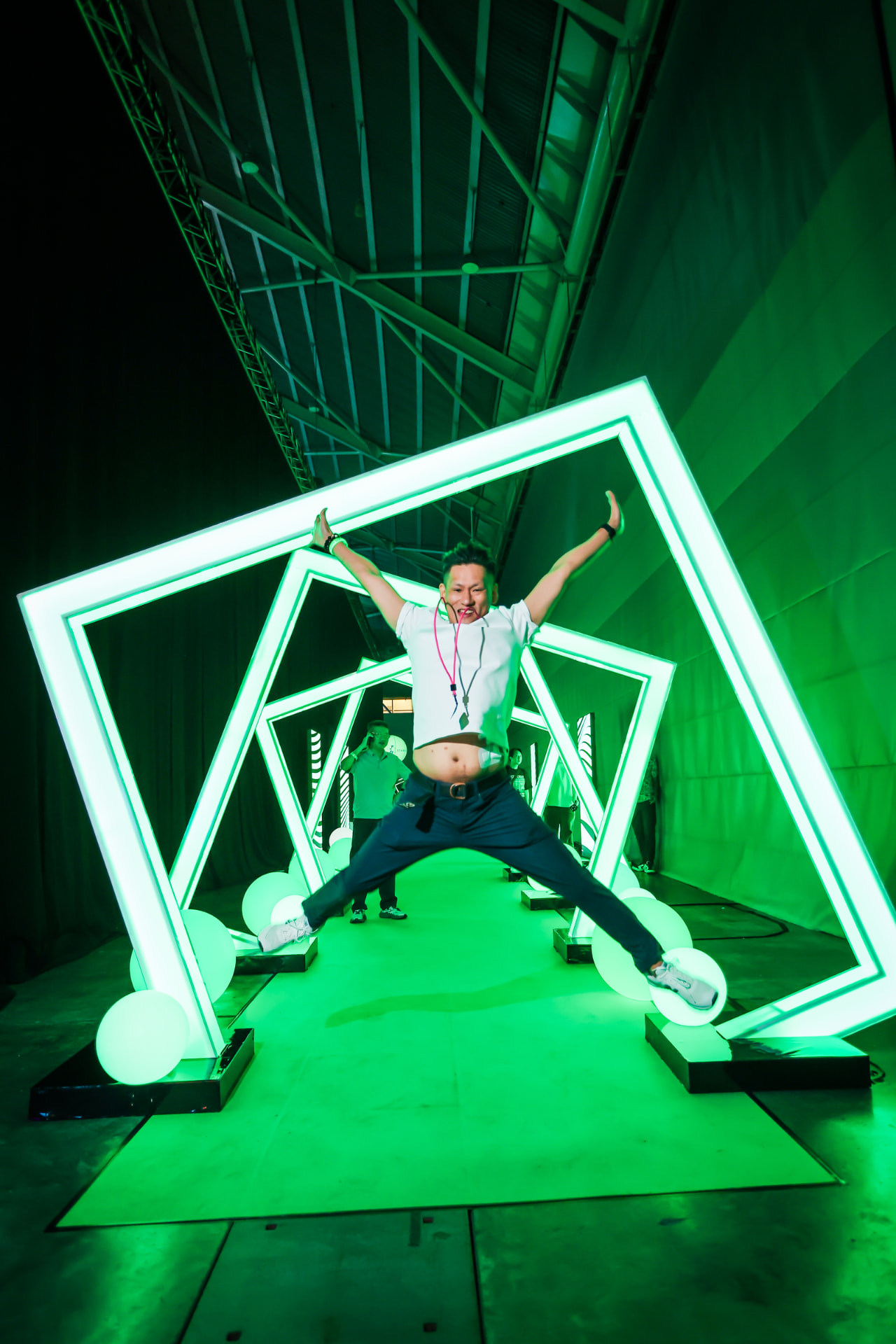 Crew member jumping through an illuminated green neon arch walkway installation